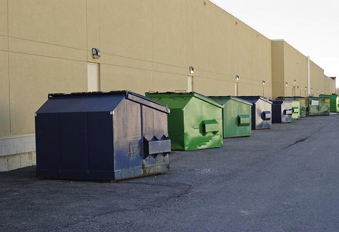 a row of yellow and blue dumpsters at a construction site in East Rockaway, NY